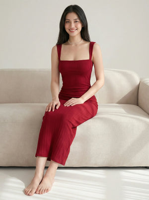 Model sitting on sofa wearing SwanClad Red Solid Sleeveless Midi Bodycon Dress highlighting elegant silhouette and midi length