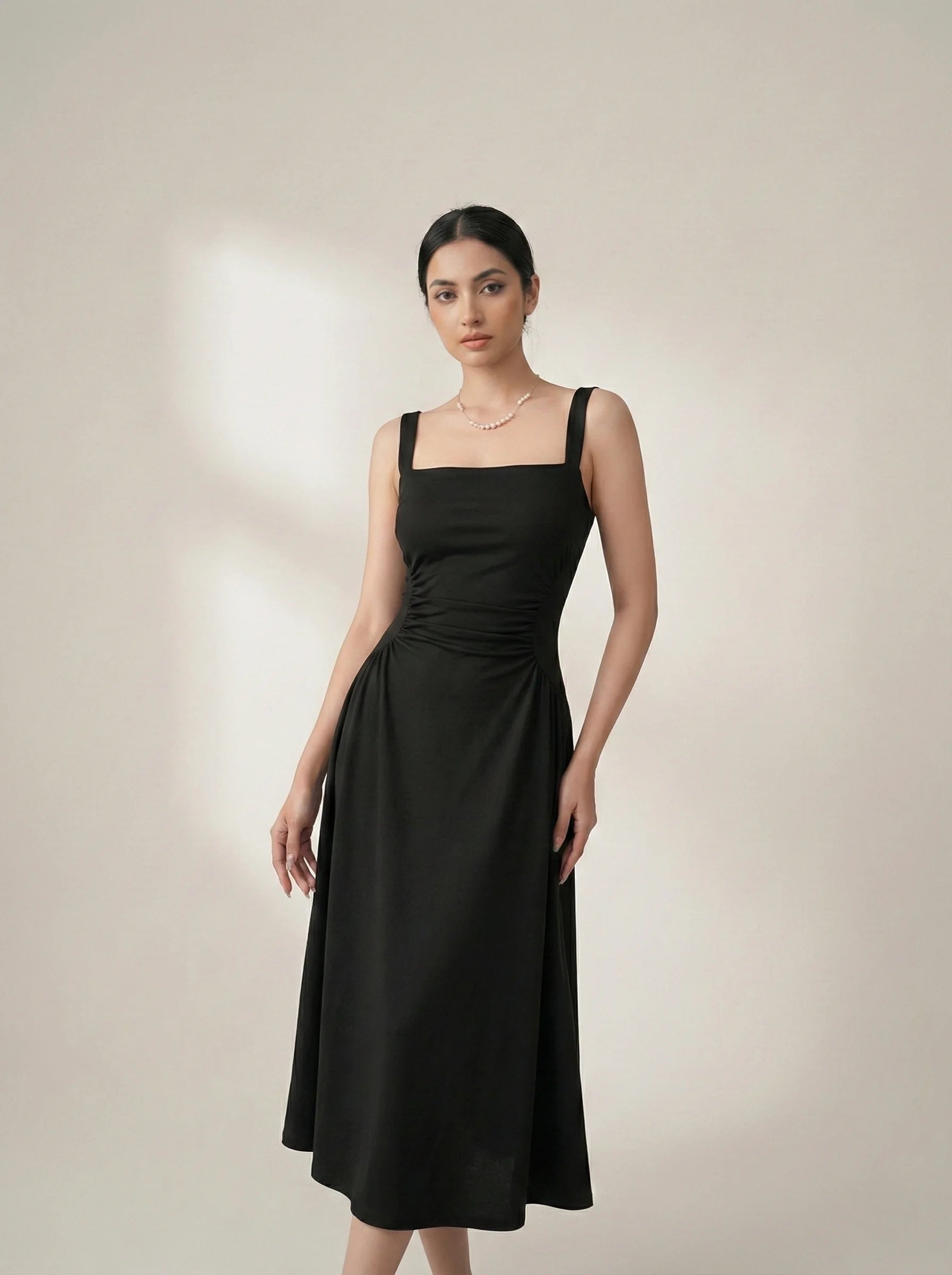 Model wearing SwanClad Black Shoulder Strapped Ruched Fit And Flare Midi Dress in angled front pose highlighting ruched waist fit