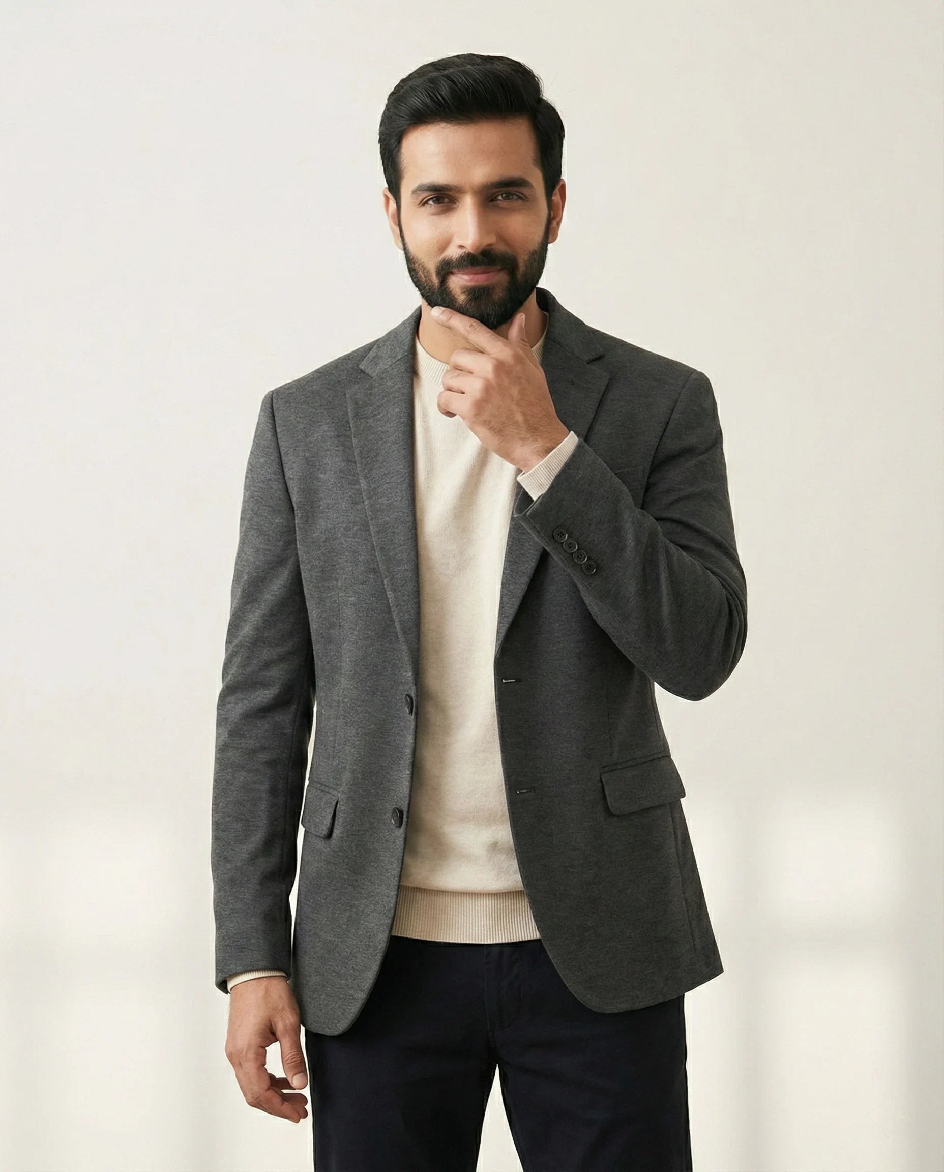 Male model in a grey blazer and cream sweater, premium smartwear styling from SwanClad.