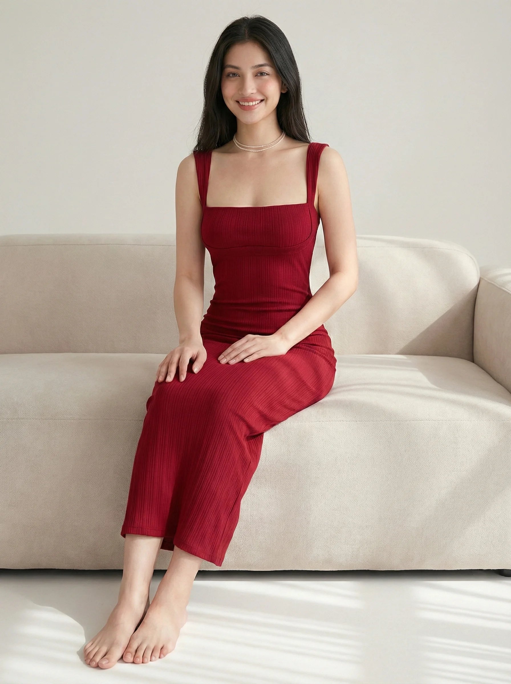 Model sitting on sofa wearing SwanClad Red Solid Sleeveless Midi Bodycon Dress highlighting elegant silhouette and midi length